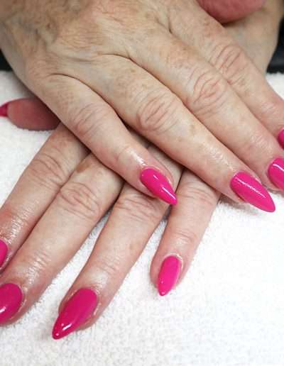 A pair of hands on top of one another with pointy pink manicured nails
