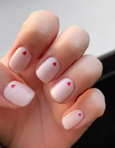 Manicured nails that are light pink with a single small heart detail above each nail bed