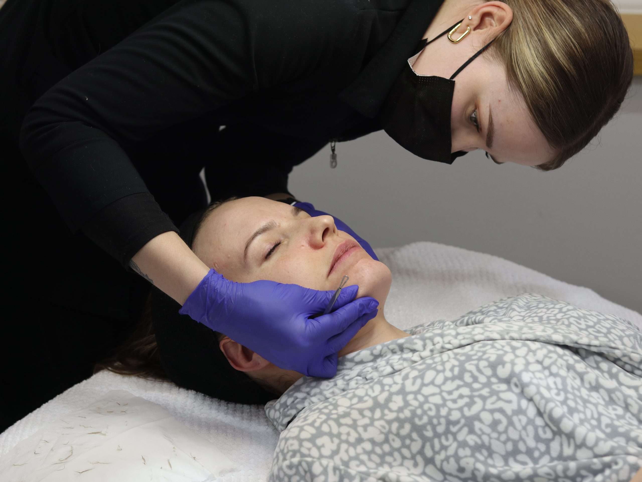 total wrapture esthetician checking client's skin before dermaplaning facial
