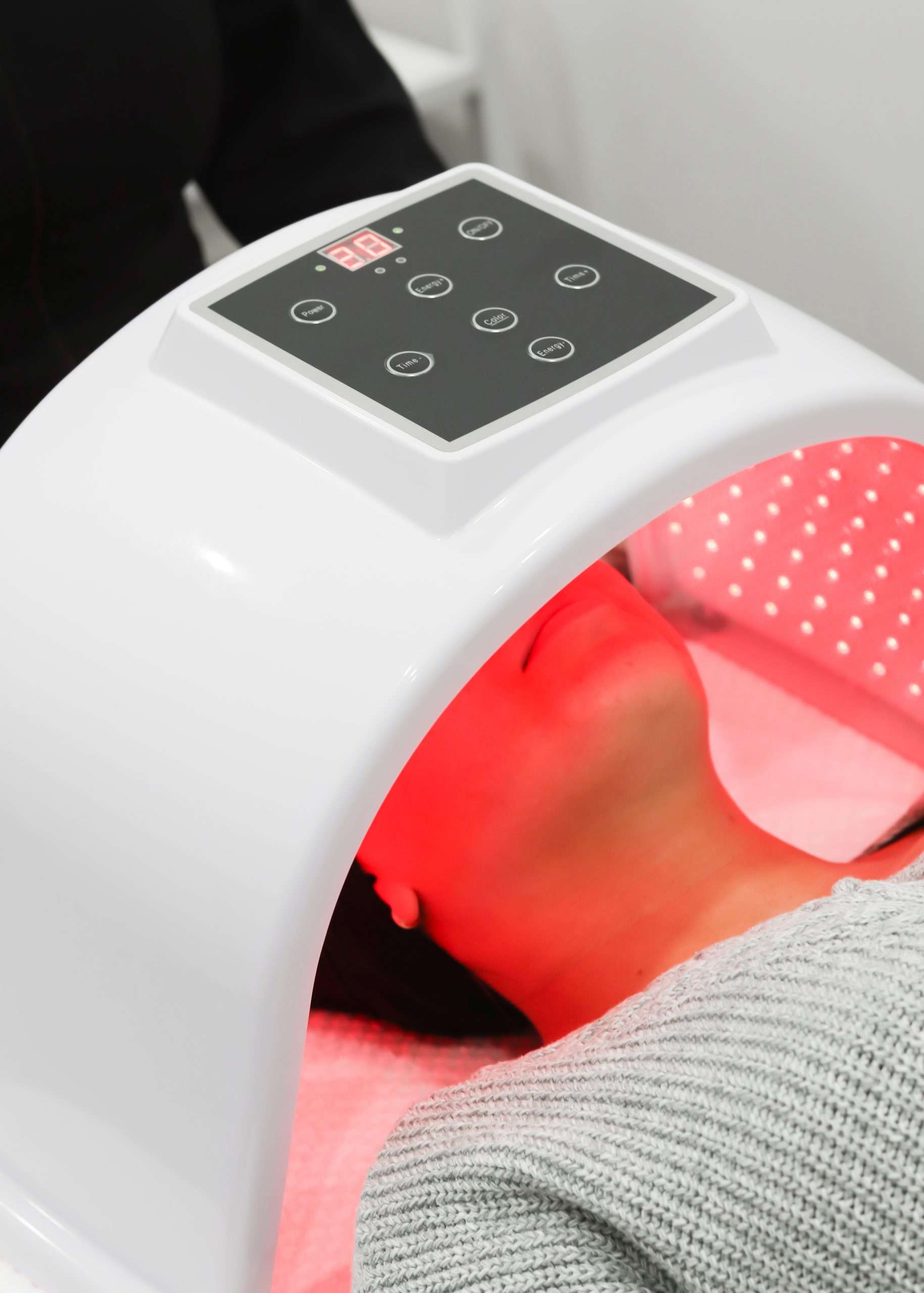 Client laying head beneath LED light therapy machine