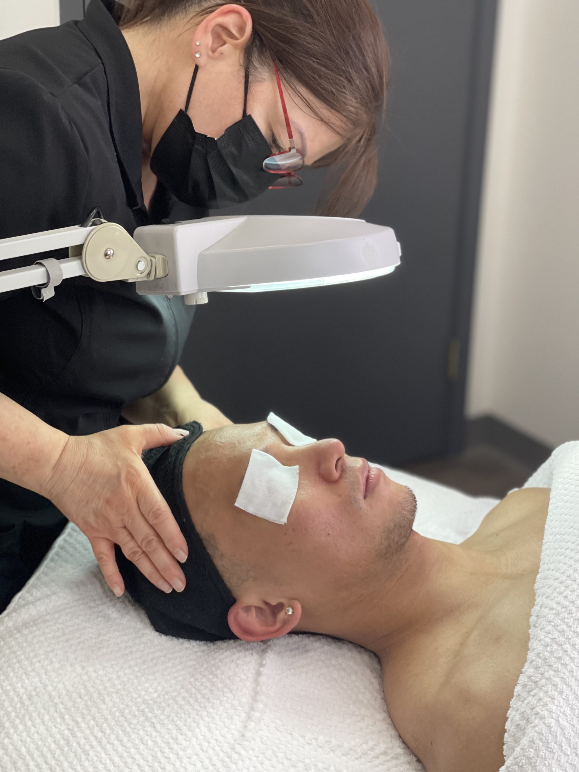 Esthetician examining client's skin