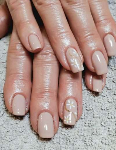 Beige manicured nails with white floral accent nail.