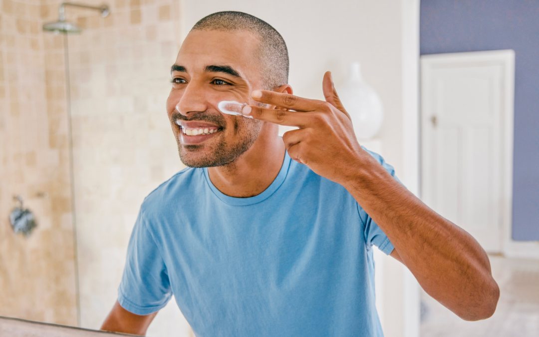 Shot of a young man applying moisturizer to his face in the bathroom at home