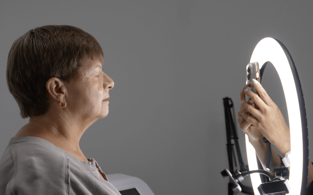 Esthetician taking a picture of a client using a ring light and an iphone.