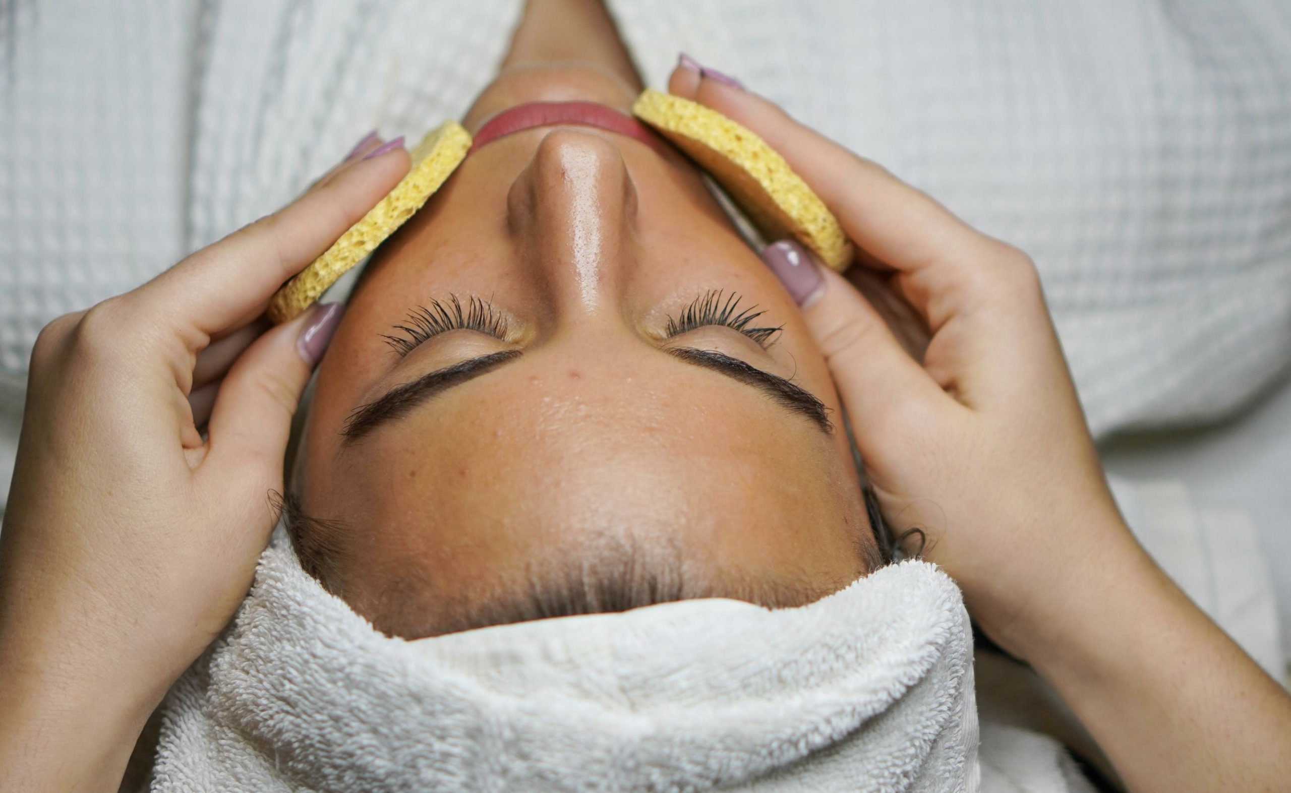 A person getting a facial cleanse with sponges during a spa treatment in Winnipeg