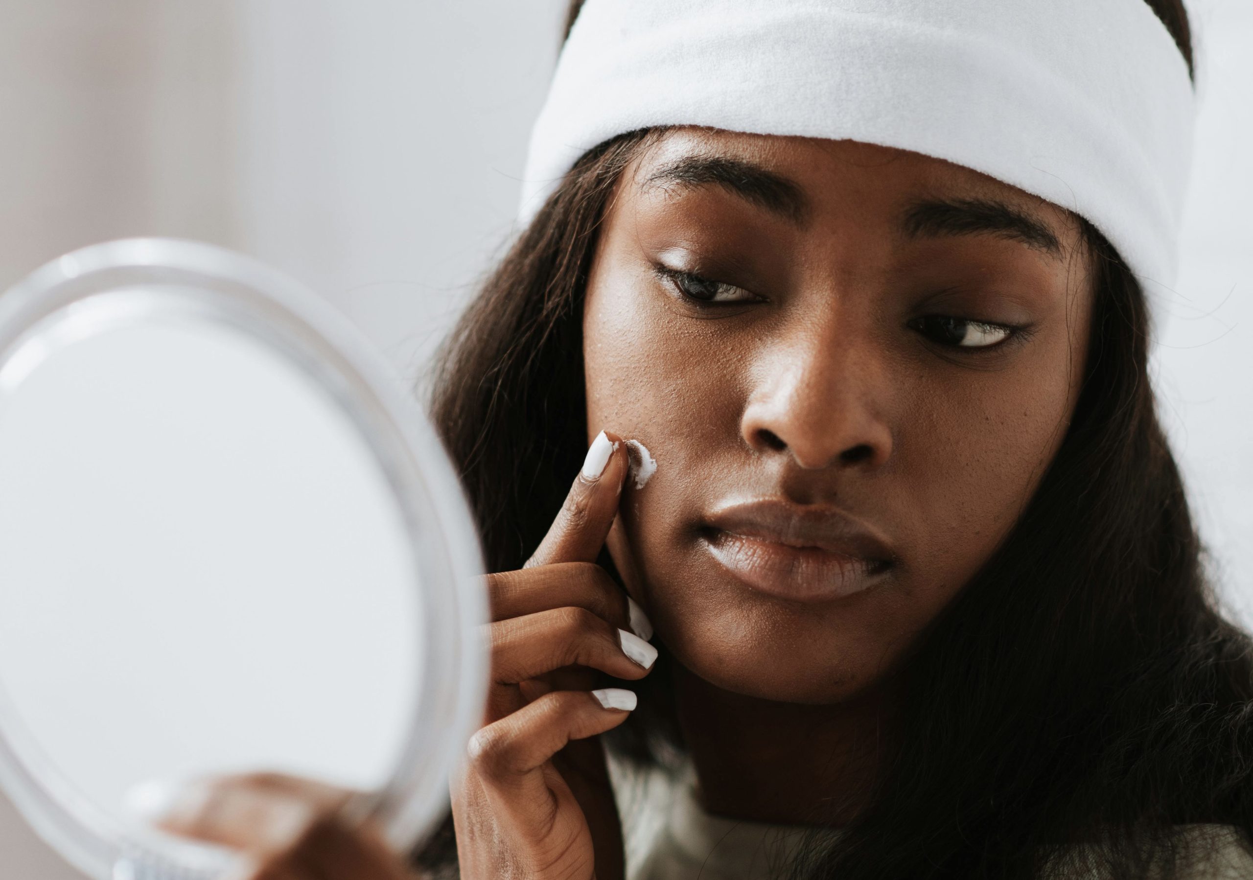 person applying skincare on their face in the mirror