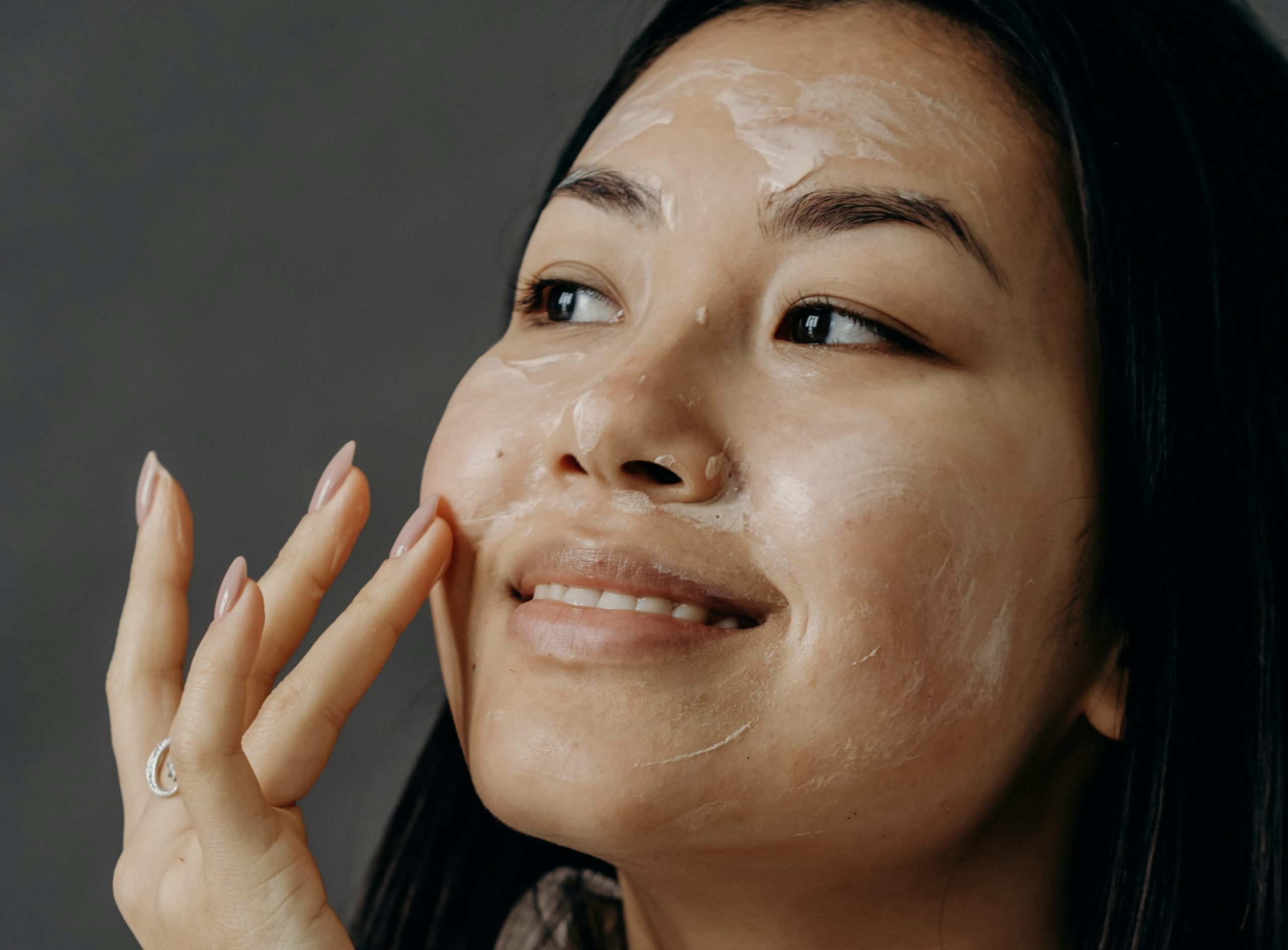 person applying skincare on their face and smiling