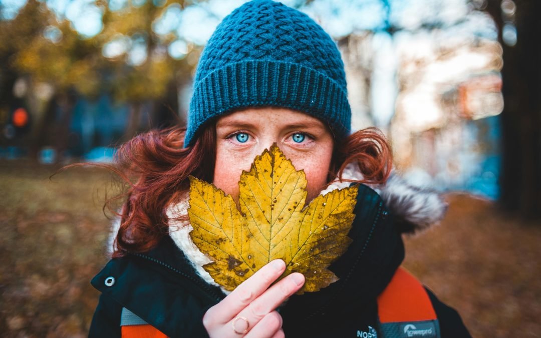 A person in Winnipeg holding up a maple leaf and tinking of SPF protection from premature aging
